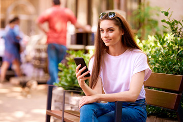 Casual young woman using mobile phone and text messaging outdoor