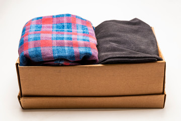 Clothes in a card box on a white background. Charity Help for people in need - box with donation clothes - Donation concept.