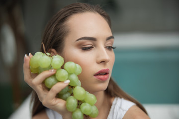 Pretty woman with grape is looking away