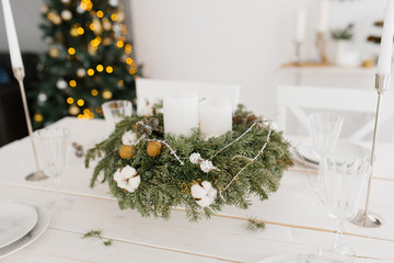 Christmas wreath with white candles on the festive table