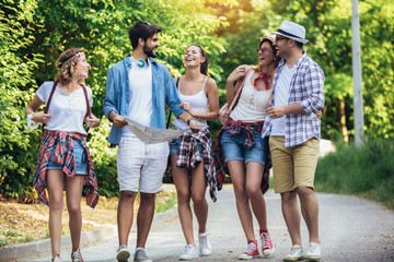 Group of young people with backpacks walking together and looking happy