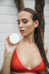 Pretty lady with wet hair holding cream