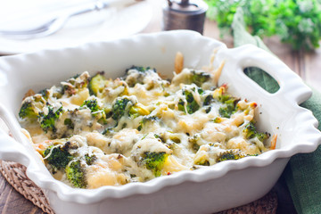 Baked broccoli with chicken in a ceramic form on a wooden table, selective focus