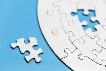 Unfinished white jigsaw puzzle pieces on blue background, The last jigsaw puzzle of success.