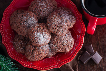 Chocolate Christmas cookies on a red plate on a wooden table, top view, selective focus