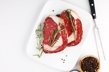 Raw fresh meat Ribeye Steak, seasoning and meat fork on rustic background