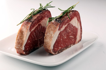 Raw fresh meat Ribeye Steak, seasoning and meat fork on rustic background