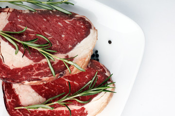 Raw fresh meat Ribeye Steak, seasoning and meat fork on rustic background