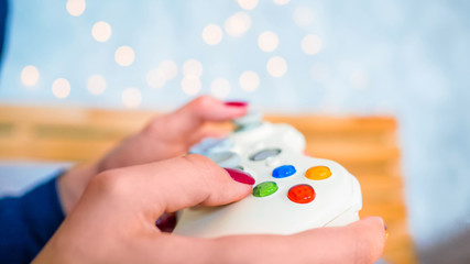 Close up shot of woman gamer hand playing video games with joystick or gamepad at home. Gaming, hobby, addiction, video game and leisure time concept
