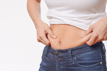 Naklejka premium Woman checking her waist for excess weight pinching her skin between her fingers