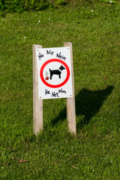 Hinweis Schild auf dem Rasen, Hunde hier nicht scheißen, in mehreren Sprachen