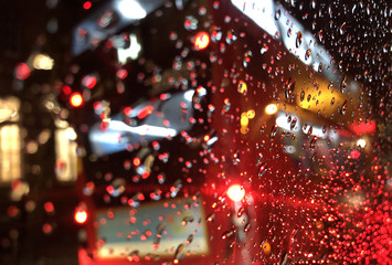 Defocussed red British bus through window on rainy day
