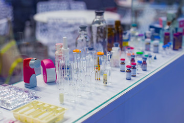 Medical empty glass bottles in showcase at pharmaceutical exhibition, pharmacy laboratory. Pharma industry, science, medicine, experiment and healthcare concept