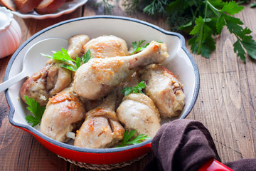 Fried chicken drumsticks in a pan on a wooden table, selective focus