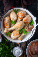 Fried chicken drumsticks in a pan on a wooden table, top view, selective focus
