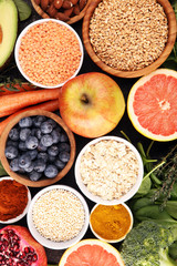 Healthy food clean eating selection: fruit, vegetable, seeds, superfood, cereals, leaf vegetable on rustic background