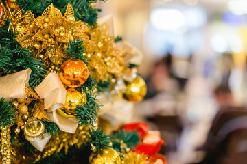 Closeup of gold bauble hanging from a decorated Christmas tree.Christmas tree celebration background.Vintage film tone.