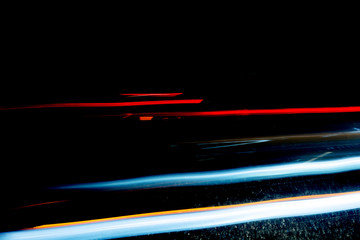 Light trails from cars passing through a dark tunnel on a rainy night