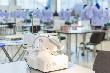 Fashion, clothing, small business, industry, needlework, manufacturing and tailoring concept. Professional tailor, fashion designer workplace - sewing machine and desk lamp on table at atelier, studio