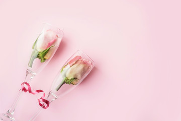 Roses in wineglasses on a pink background. Background for holiday, birthday, wedding, Valentine's day, Women's Day. Top view, flat lay composition. Copy space for text or design.