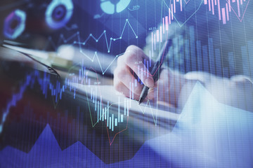 Financial forex graph displayed on hands taking notes background. Concept of research. Multi...