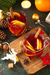 Winter Christmas mulled wine with orange and spices on the festive table.