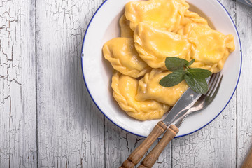 Ukrainian dumplings, pierogi or pyrohy, varenyky, vareniki, served with cottage cheese on board. National Russian cuisine, natural organic homemade bakery product, view from above.