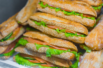 Close up view - assortment of sandwiches with lettuce, salmon for sale on counter of market, cafe,...