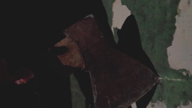 scary hand holding an ax holds an ax along an old destroyed brick wall