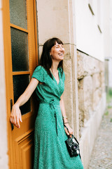 Fototapeta premium elegant woman wearing a green dress is laughing with an old film camera in her hands