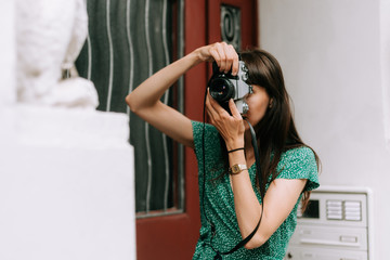 elegant woman wearing a green dress is taking a picture with an old film camera