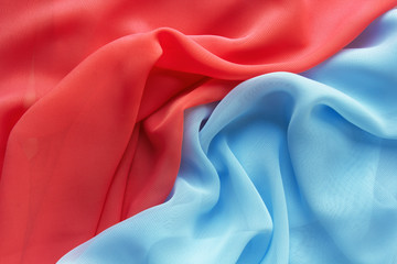 red and light blue fabric with large folds as background