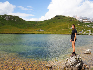 attractive brunette in her twenties standing on a boulder in a mountain lake