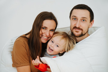 Portrait of a happy family wrapped up in a blanket. Mom, dad and their son.