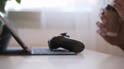 Coffee or hot drink break after playing video game by using controller or joystick for computer tablet at cafe