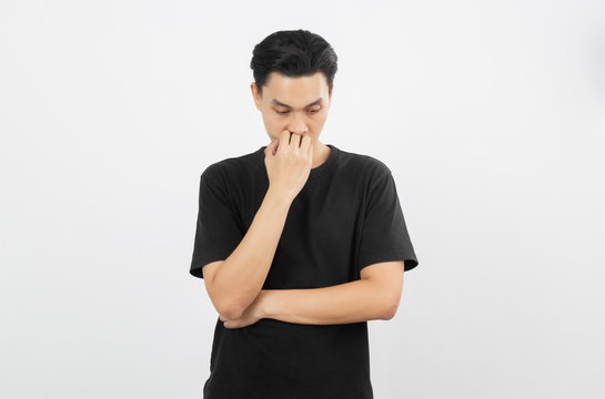 Young handsome asian man with black shirt unhappy with hand covering mouth isolated on white background.