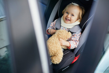 Adorable toddler girl in modern car seat