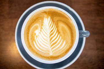 cup of coffee with cream on wooden background