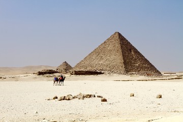 Two camels with the rider walking in front of the Pyramid of Giza one of the 7 wonders of ancient world 