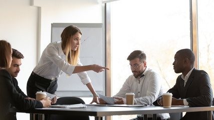 Mad businesswoman scolding biracial worker at meeting