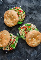 Focaccia sandwich with green salad, grilled chicken, avocado tomato salsa and yogurt sauce on dark background, top view