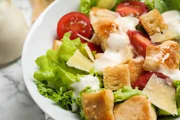 Tasty Caesar salad with chicken on table, closeup