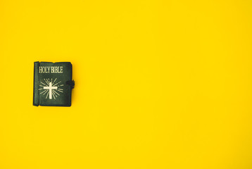 Top view of Holy bible on yellow background.