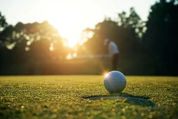 Rolgordijnen Blurred golfer playing golf in the evening golf course, on sun set evening time. © somchai
