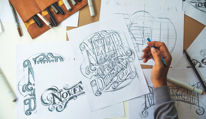 Typography Calligraphy artist designer drawing sketch writes letting spelled pen brush ink paper table artwork.Workplace design studio.