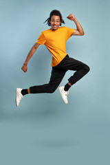 Fototapeta na wymiar African American man jumping high, happy lucky young guy having fun