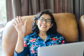 55 years old senior woman.Portrait of senior woman on sofa and say hi.Senior Adult Women Smiling...