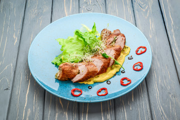 grilled meat with sauce and stewed vegetables on a wooden table