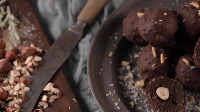 Dark chocolate truffles with hazelnuts and chopped hazelnuts over wooden cutting board.