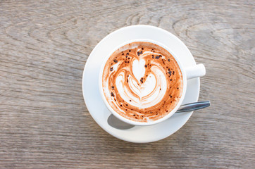 Top view Hot coffee Espresso topped with a heart shaped milk in white glass on wooden table.